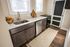 Bright kitchen with sleek countertops, modern stainless steel appliances, and a cozy rug enhancing warm wooden floors.