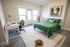 Bright bedroom with modern green bedding, cozy workspace, and stylish decor, perfect for comfortable living.
