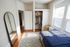 Bright and cozy bedroom featuring a stylish open closet, full-length mirror, and large windows for natural light.