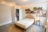 Cozy bedroom with modern decor featuring a chic wooden bed, vibrant string lights, and a stylish open closet. Enlivened by indoor plants and a creative pinboard, this serene space offers a perfect blend of comfort and style.