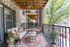 Charming apartment balcony with cozy seating, stylish decor, and a scenic view of lush greenery, perfect for relaxation.