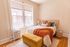 Bright and cozy bedroom with large windows, warm lighting, and elegant decor featuring a plush bed and vibrant accents.