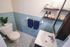 Charming bathroom adorned with soothing blue tiles, featuring elegant shelving, plush towels, and a touch of greenery for a serene ambiance.