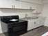 Modern kitchen with sleek black appliances, pristine white cabinetry, and a stylish marble countertop.