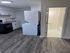 Modern kitchen with white cabinetry, sleek flooring, and a convenient in-unit washer and dryer next to a stylish bathroom.