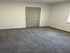 Chic apartment room with plush gray carpeting and a modern, neutral-toned door, offering a serene and inviting atmosphere.
