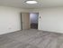 Bright and cozy room with soft carpet flooring, modern lighting, and an inviting open door leading to a hallway.