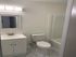 Elegant bathroom with a modern vanity, sleek faucet, and bright lighting. Features a pristine bathtub and chic tile flooring.