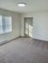 Bright and spacious room with plush carpet, modern ceiling light, and sunlit windows, perfect for a cozy retreat.