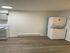 Modern kitchen with sleek appliances and in-unit laundry, featuring chic hardwood flooring and bright lighting.