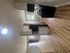 Bright and modern kitchen with sleek cabinets and stainless steel appliances, opening to a spacious living area with elegant wood flooring and abundant natural light.