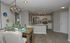 Chic open-concept kitchen and dining area with stylish lighting, rustic wooden table, and modern appliances.