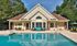 Charming clubhouse with inviting pool and cozy outdoor seating, surrounded by lush greenery for a serene living experience.