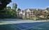 Elegant apartment complex with lush greenery and a well-maintained tennis court, perfect for active living.