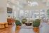 A warm and inviting clubhouse living space featuring chic green lounge chairs, an elegant round coffee table, and expansive sunlit windows that showcase serene views