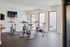 Modern fitness room with bright natural light featuring stationary bikes and a wall-mounted TV for an invigorating workout experience.