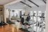 Modern apartment gym with state-of-the-art equipment, treadmills overlooking scenic views, and high ceilings with stylish beams.