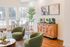 Elegant clubhouse featuring chic green chairs, a stylish wooden console, and expansive windows that fill the space with natural light. A perfect blend of modern décor and cozy ambiance