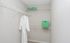 Spacious walk-in closet with ample shelving, featuring a plush white robe and vibrant green storage boxes for stylish organization.