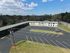 Bright aerial view of a modern apartment complex with spacious parking and lush surroundings, perfect for convenient urban living.