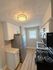 Modern kitchen with sleek stainless steel appliances, elegant cabinetry, and wood-style flooring, illuminated by contemporary lighting.