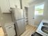Bright, modern kitchen with sleek stainless steel refrigerator, elegant white cabinetry, and pristine marble countertops.