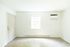 Bright, airy room with modern flooring, a large window, and an air conditioning unit, perfect for comfortable living.