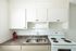 Charming kitchen with sleek cabinets, a modern double sink, and a classic white stove, accented by a stylish marble countertop.