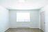 Bright, open bedroom with natural light streaming through large window, featuring elegant wood flooring and modern, neutral decor.