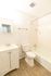 Bright and modern bathroom featuring sleek white fixtures, elegant wood-style flooring, and a classic bathtub with shower.