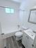 Bright bathroom featuring a sleek white bathtub, modern vanity, and elegant wood-style flooring.