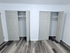 Modern apartment space showcasing dual spacious closets with elegant double doors and sleek wood-style flooring.