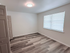 Bright, spacious bedroom with elegant light fixture and chic wood flooring, perfect for personalization and comfort.