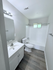 Pristine bathroom with elegant white fixtures, modern sink vanity, and stylish wood flooring, offering a serene atmosphere.