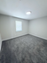 Bright and inviting room with plush carpet flooring and a large window offering ample natural light.