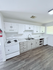 Chic apartment kitchen with modern white cabinetry, sleek countertops, and elegant wood flooring.