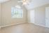 Bright spacious room with vaulted ceiling, featuring a large window, light wood flooring, and ceiling fan.