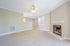 Bright and inviting living room with elegant fireplace, ceiling fan, and open-concept layout leading to a modern kitchen.