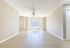Bright and spacious living area featuring elegant wood floors, large bay windows, and a ceiling fan for comfort.