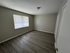 Inviting bedroom with sleek hardwood flooring and soft natural light streaming through large windows.
