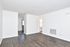 Bright and spacious living area with elegant dark wood flooring and crisp white walls, featuring clean lines and modern design.