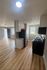 Bright, open kitchen with stainless steel appliances and modern wood flooring leading to a spacious living area.