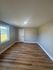 Bright, unfurnished room with elegant wood flooring, large window, and gray walls, ideal for customization.