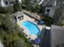 Inviting aerial view of a sparkling kidney-shaped pool surrounded by lounge chairs, umbrellas, and lush greenery, ideal for relaxation.