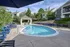 Charming apartment complex with a refreshing swimming pool surrounded by stylish lounge chairs and lush greenery.
