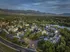 Aerial view of a picturesque apartment community surrounded by lush greenery and set against stunning mountain vistas, featuring modern buildings and serene pathways.
