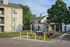Charming apartment complex with modern outdoor seating area surrounded by lush greenery and mature trees.