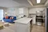 Modern apartment interior featuring stylish kitchen with marble countertops, cozy living room with vibrant blue sofa, and bright bedroom access. Contemporary design with natural light and sleek finishes.