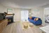 Inviting living space with a vibrant blue sofa, colorful cushions, and a cozy fireplace, enhanced by natural light from sliding glass doors.