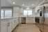 Sleek modern kitchen with white cabinetry, stainless steel appliances, and large window with city view.